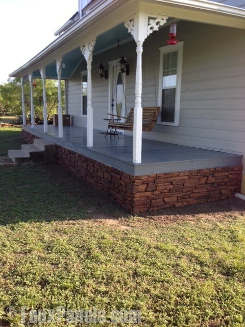 A residential front porch with brown faux stacked stone panels placed in the gap area.