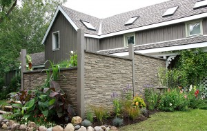 Privacy fence built with wooden framing and fake stacked stone panels in Kentucky Gray.