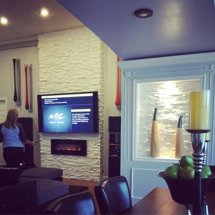 A sauna's lounge area with fireplace, TV and recessed alcove covered with Wellington Dry Stack in Washed Bisque color.