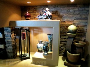 Recessed lighting and drystack stone style panels added to a fireplace shelving unit.