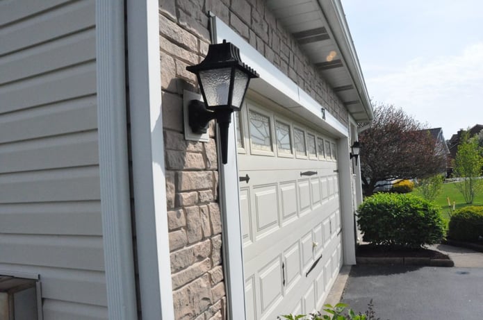 This picture demonstrates the dramatic contrast between regular vinyl siding and faux rock siding.