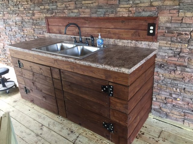 Screened in porch design with stacked stone accent wall and custom timber plank kitchenette. 
