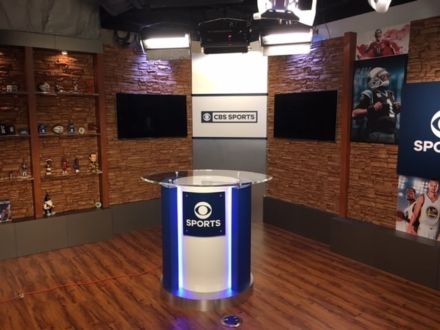 CBS Sports studio with backdrop wall covered in faux stacked stone panels.