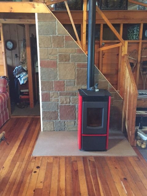 Wood stove in Maine log cabin backed by Carlton Castle Rock panels cut to size and installed on the backing staircase.