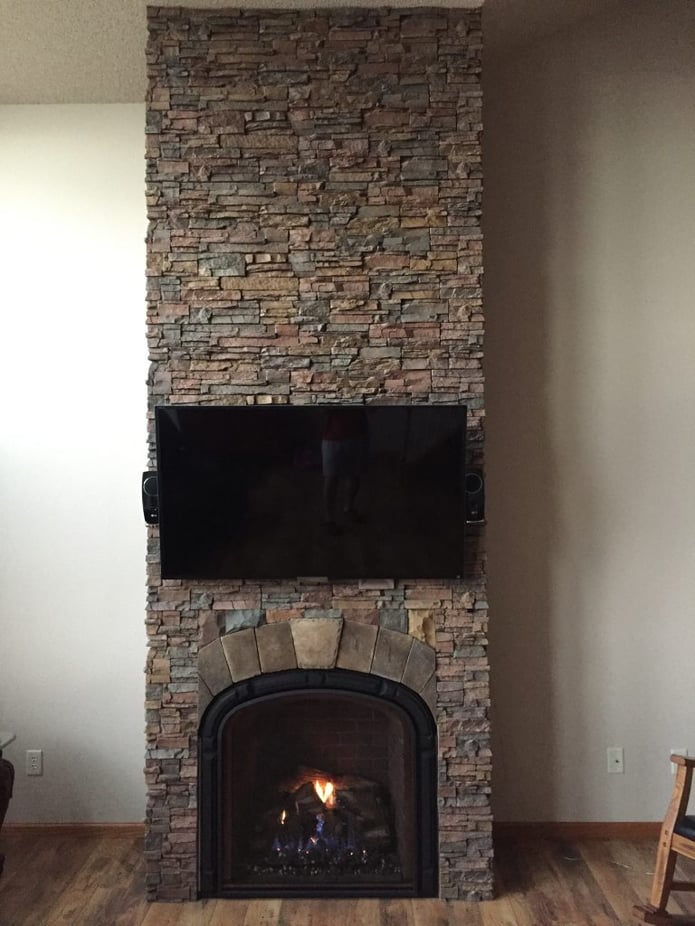 A home's fireplace and interior chimney covered in panels with a stacked stone finish.