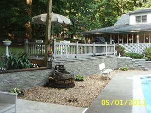 Faux stone wall siding added to a poolside retaining wall to greatly enhance the backyard design