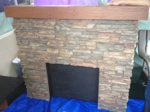 Scrap panels were transformed into a faux stone fireplace with mantel for a play. This great looking fake fireplaces was designed with a wood framework to hold our faux panels and the faux wood beam used for a mantel.
