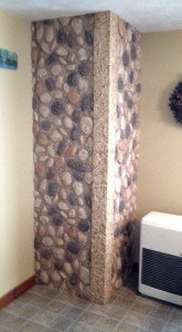 Corner unit covered in river rock style panels as part of a small bathroom remode.