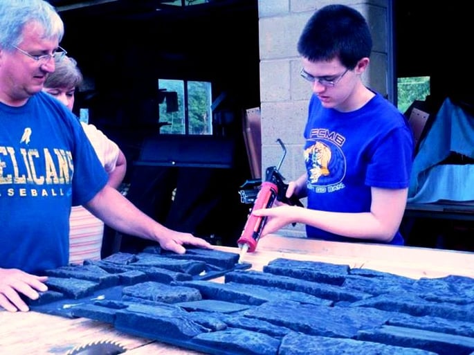 Venture Crew 630 member glues the panels together before putting them up on the playhouse.