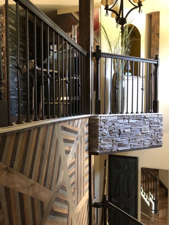 Mezzanine with iron railing and stacked stone panels applied to the overhang