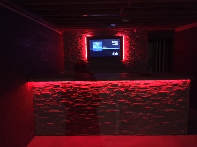 Basement bar idea: wooden frame finished with stacked stone style panels and hidden LED lights.