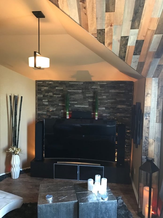 Living room TV backed by a stacked stone style accent wall.