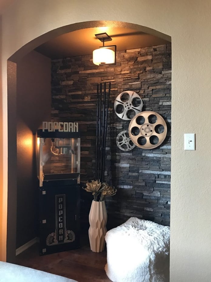 Home theater with stacked stone veneer accent wall and popcorn machine.