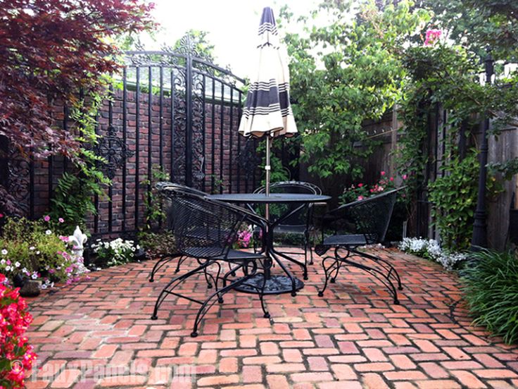 Secret Garden-esque enclosed patio area with wrought iron furniture and fence