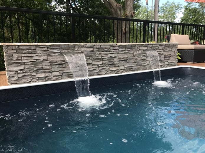 Closeup view of poolside water featured covered in stone style panels.