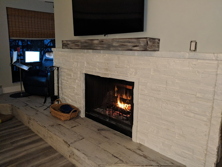 Faux white stone panels create a fireplace surround, fitting in with the home's beachy decor.