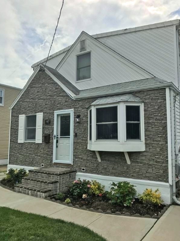 Home exterior with new landscaping, fixtures and partially refaced with Norwich Stacked Stone panels in Gray Rock color.