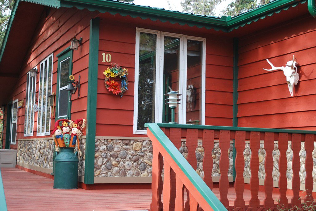 Red clapboard cabin with rock siding installed on the lower exterior